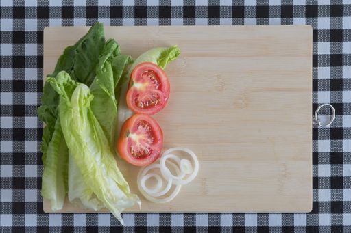 A top view of assorted vegetables on a wooden board, with a black and white checkered tablecloth
