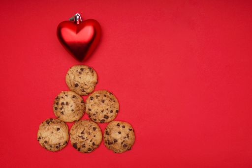 A top view of a Christmas tree made of chocolate chip cookies with a heart shaped ornament on the top