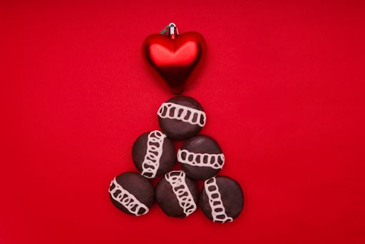 The chocolates decorated like a Christmas tree with a heart-shaped red ornament on a red surface