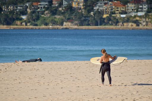 Sydney / Australia - May 11 2019: View of woman carrying surfboard at Manly Beach