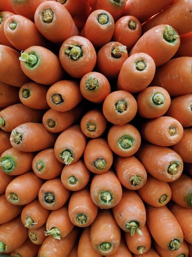 A vertical closeup shot of a lot of fresh carrots in a market