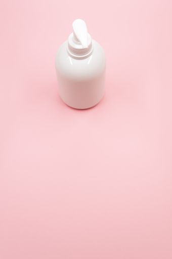 A white antiseptic pump bottle on a light pink background