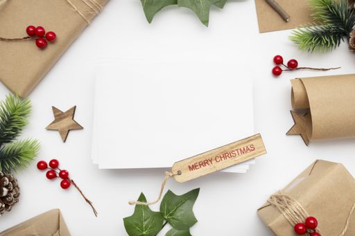 A top view of wrapped gifts, holly berry plants, pine cones, Merry Christmas tag with copy space isolated on a white background