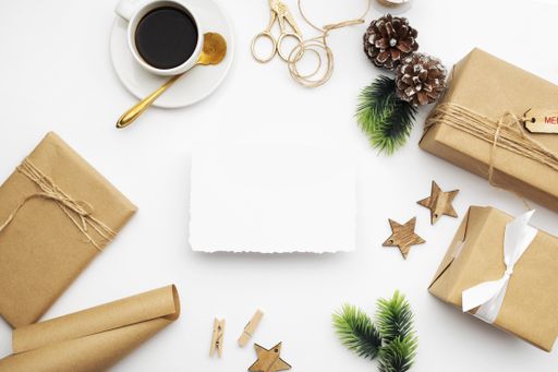 A top view of wrapped gifts, fir branches, pine cones, and a cup of coffee with copy space isolated on a white background