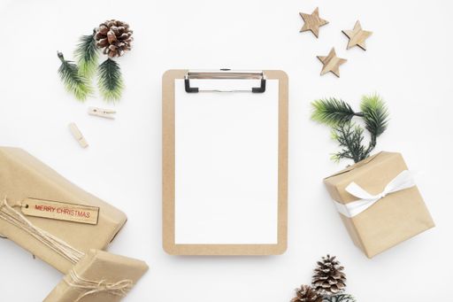 A top view of wrapped gifts, fir branches, pine cones, and clipboard for Christmas with copy space isolated on a white background