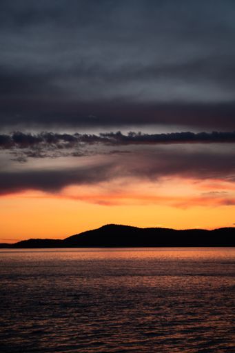 A vertical shot of the sea with San Juan Islands in the background during sunset, Anacortes, Washington