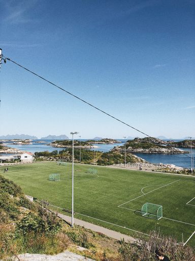 A vertical shot of a soccer field in the middle of the sea full of cute little islands