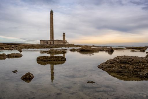 A beautiful shot of a lighthouse reflecting in the ocean during sunset