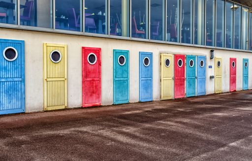 An outdoor hallway with doors of different colors with a nice modern cafe above