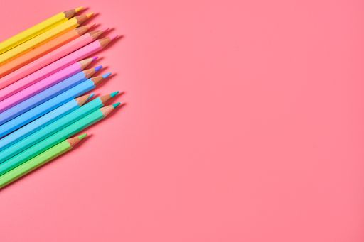 A closeup shot of colored pencils on a pink background with copy space