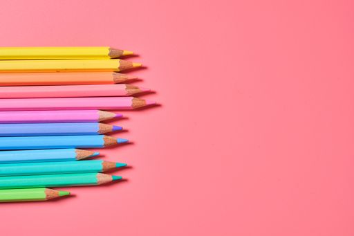 A closeup shot of colored pencils on a pink background with copy space