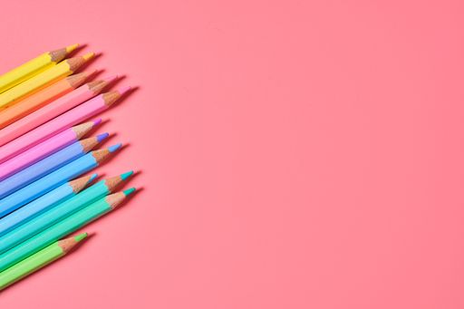A closeup shot of colored pencils on a pink background with copy space