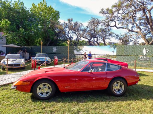 Old red sport 1970s Ferrari 365 GTB Daytona berlinetta in a park. Nature, grass, trees. Autoclasica 2022 classic car show.