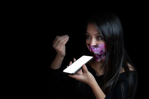 A brunette with a shocked or excited expression wearing a face mask and sending a voice message