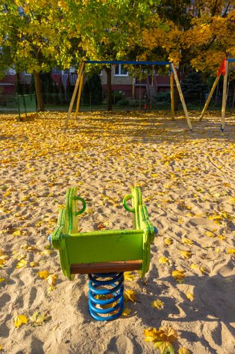 A vertical shot of a spring swing  set on a sandy playground with autumn colors in Poznan, Poland