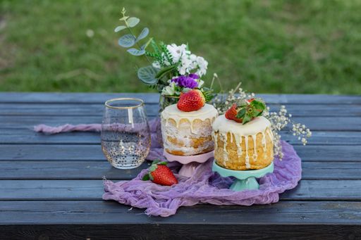 A selective shot of a small picnic on a wooden table in the park with strawberry sponge cake