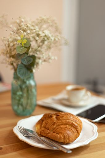 A selective focus shot of breakfast table with croissant coffee and newspaper