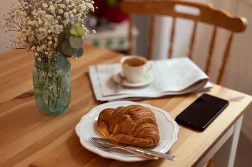 A selective focus shot of breakfast table with croissant coffee and newspaper