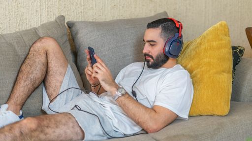 A Caucasian bearded man chatting with his phone and laying on the sofa