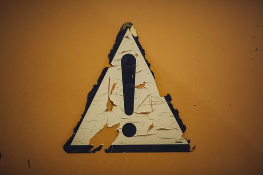 A rusty weathered exclamation mark on a yellow background