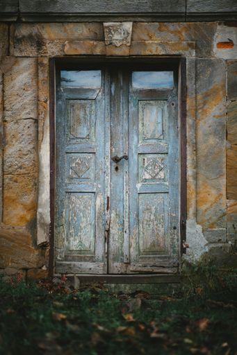 A vertical shot of an ancient blue wooden door in an old building with interesting textures