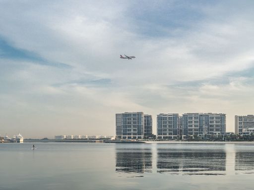 An airplane flying over the Al Zeina neighbourhood as it approaches Abu Dhabi International airport to land