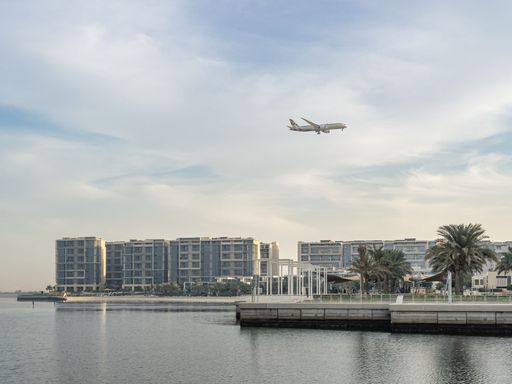 An airplane flying over the Al Zeina neighbourhood as it approaches Abu Dhabi International airport to lan