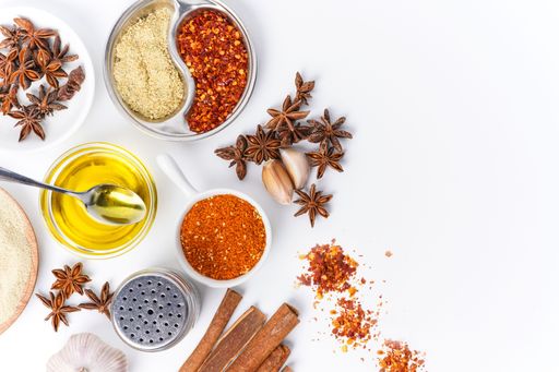 A top view of different spices with Sichuan peppercorns, cloves, and Chinese cinnamon on a white background