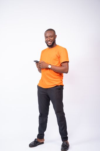 A cheerful young Nigerian man texting with his phone isolated on a white background