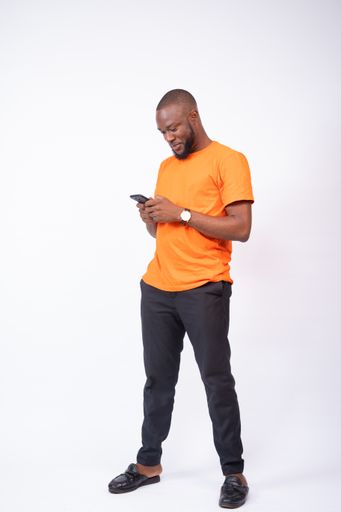 A cheerful young Nigerian man texting with his phone isolated on a white background