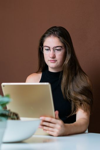 A vertical shot of a young European woman video chatting using a tablet at home