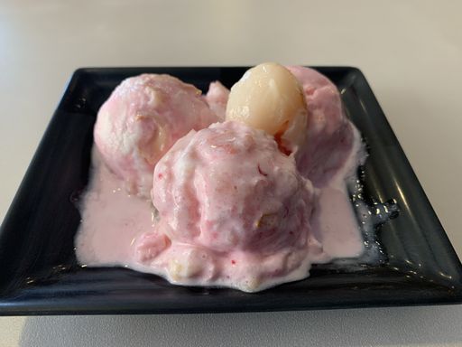 a closeup top shot of pink ice cream on a black plate