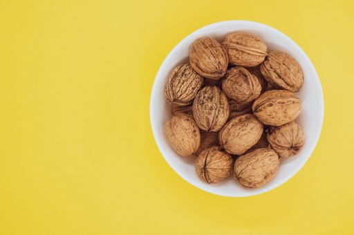 A top view of walnuts on a white bowl isolated on a yellow background