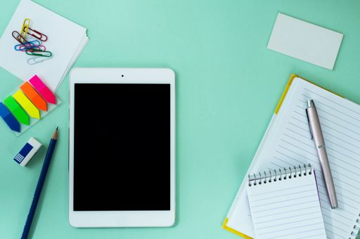 The flat lay of a tablet and creative office supplies on the light blue background