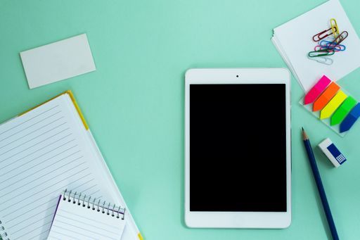 The flat lay of a tablet and creative office supplies on the light blue background