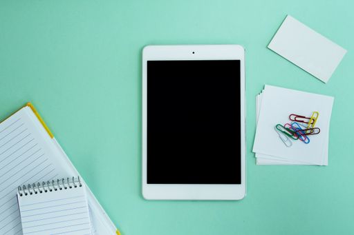 The flat lay of a tablet and creative office supplies on the light blue background
