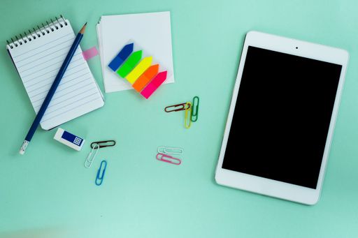 The flat lay of a tablet and creative office supplies on the light blue background