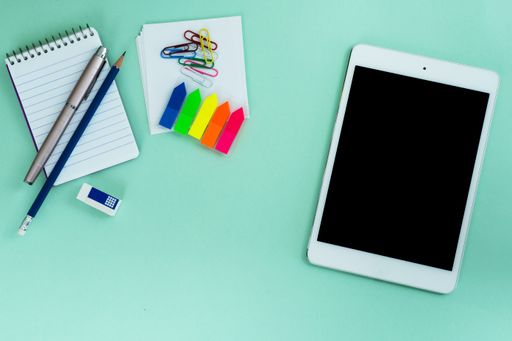 The flat lay of a tablet and creative office supplies on the light blue background