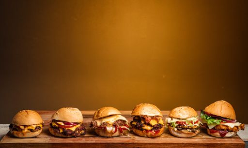A closeup shot of different delicious burgers on a wooden board