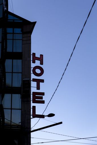 A vertical shot of a Hotel sign on a building with clear blue sky