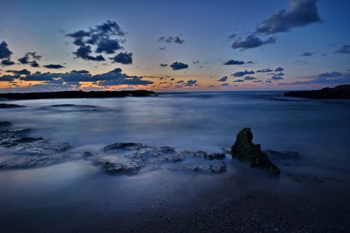 A landscape of the sea with long exposure surrounded by rocks in the evening