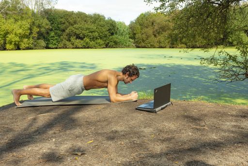 A Caucasian man in an online pilates class in the park
