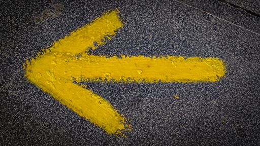 A yellow arrow on a wall indicating to pilgrims the direction to walk in Saint Jacob way, Camino de Santiago, Spain