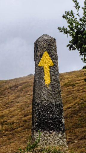 A yellow arrow on a stone indicating to pilgrims the direction to walk in Saint Jacob way, Camino de Santiago, Spain