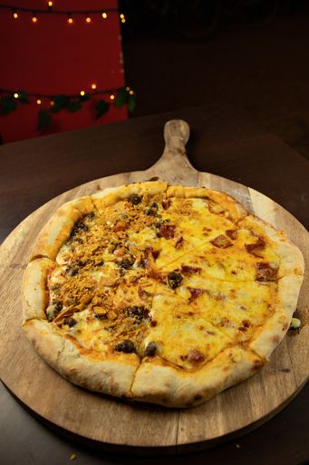 A vertical shot of a whole delicious pizza with melted cheese and mushrooms on a wooden board