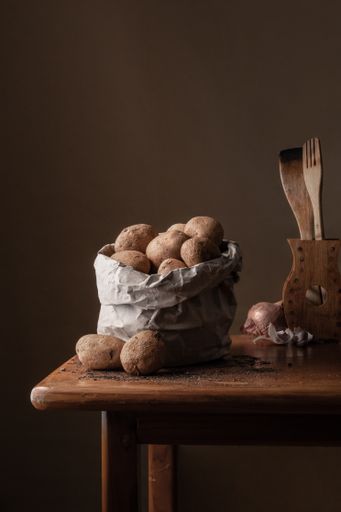 A closeup of a bag of potatoes and wooden kitchen utensils, the kitchen still life