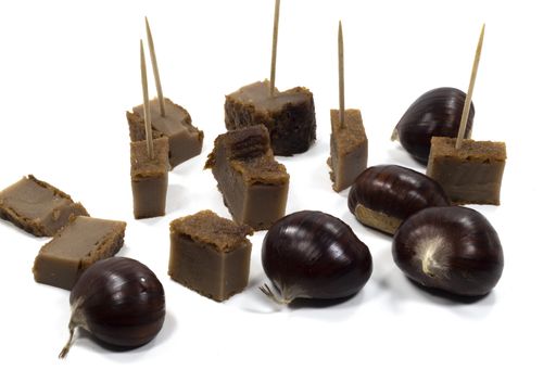 A closeup shot of chestnut cakes on toothpick and chestnuts isolated on a white background