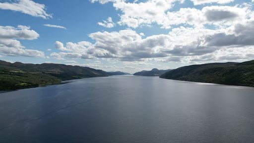 An aerial view of Loch Ness under blue cloudy sky in the Scottish Highlands, UK