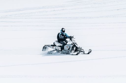 A male riding a snowmobile in a large snowy field