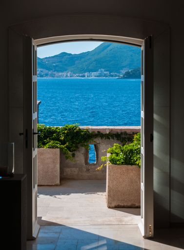 A vertical shot of a balcony door overlooking a beautiful sea on a sunny day